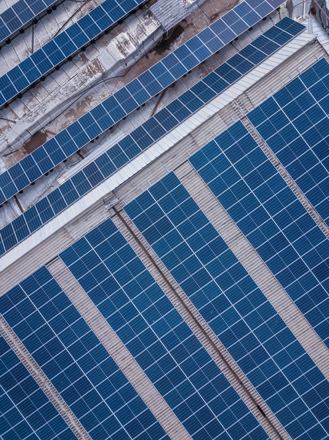 Rows of blue solar panels on a commercial rooftop.