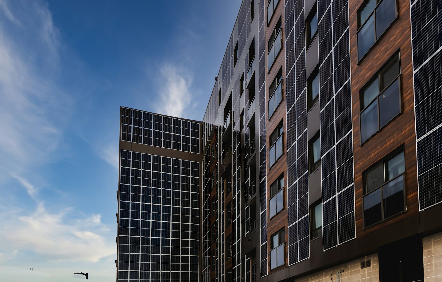 Modern building facade with solar panels and wood cladding.